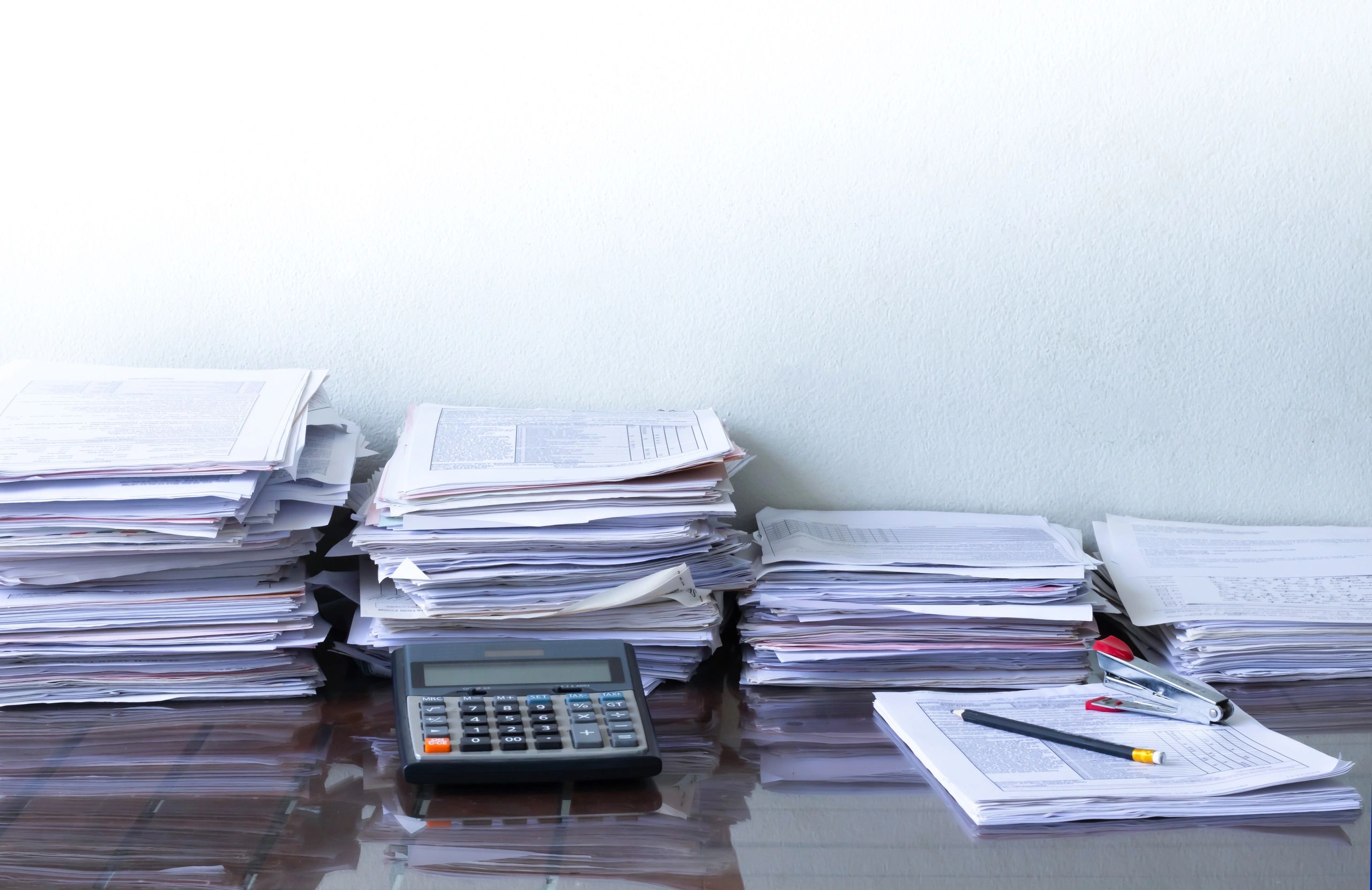 Paperwork stack with calculator and pen representing required GST documents